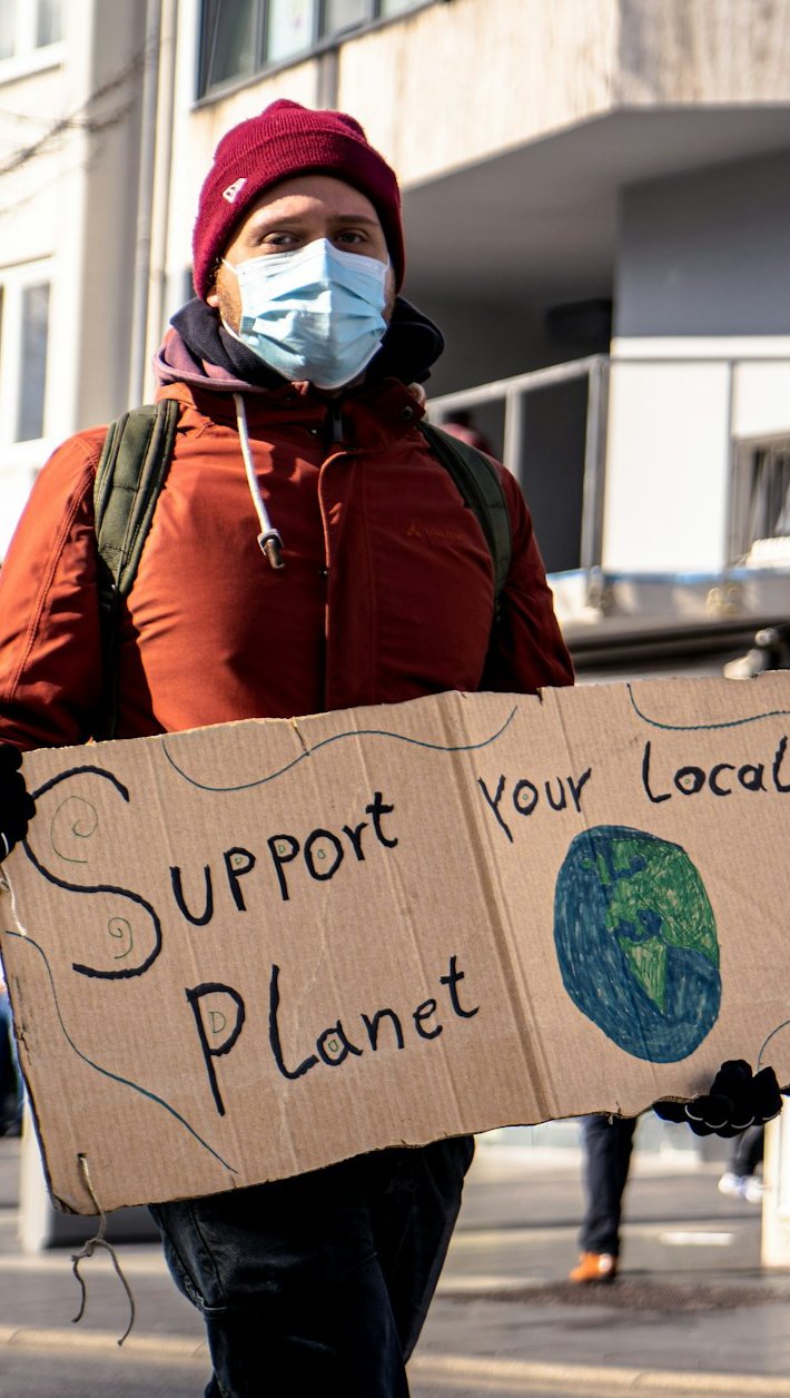 Man holding a sign that says 'Support your local planet'